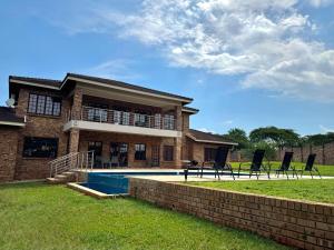 a brick house with a swimming pool and two chairs at Avocado Grove Guest House in White River