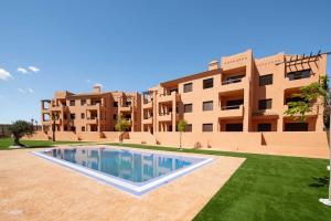 a swimming pool in front of a building at Serena Golf Apartments in Los Alcázares