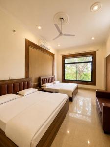 a bedroom with two beds and a window at Hotel Vasant - Premium Hotel in Gajraula - All AC Rooms with Restaurant - Free Wi-fi & Parking - Banquet in Gajraula