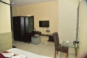 a hotel room with a desk and a television at Hotel 4G in Bhopal