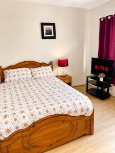 a bedroom with a wooden bed with a nightstand and a tv at Cosy room in Wolverhampton perfect for contractors in Wolverhampton