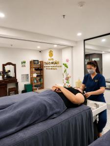 a woman in a room with a patient on a bed at Thảo Ngân Pleiku Hotel in Pleiku