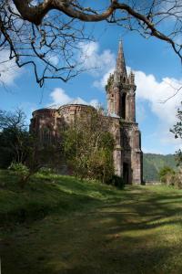 an old building with a tower on a grass field at Casa Dos Barcos Furnas in Furnas