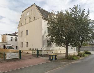 a white building with a tree next to a street at Seyfarthrooms - Crimmitschau 3 - zentrale Lage, gute Anbindung, voll ausgestattet in Crimmitschau