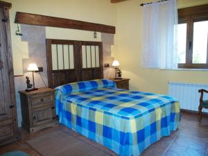 1 dormitorio con 1 cama con manta azul y amarilla en El Porma en Villanueva del Condado