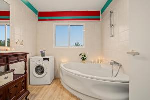 a bathroom with a white tub and a washing machine at casa Jardín del sol planta alta in Tacoronte +21 photos