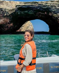 a woman standing on a boat in front of a cave at El Candelabro in Pisco