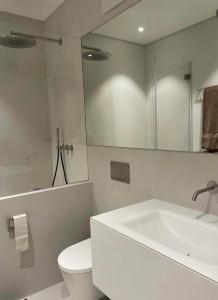 a white bathroom with a toilet and a sink at Casa Rok in Flims +6 photos