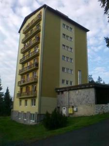 un edificio alto de color amarillo con balcones en un lateral en Apartment LULU, en Štrbské Pleso