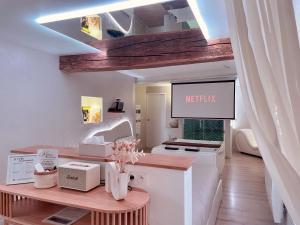 a kitchen with a tv on the wall and a table at Les Jolies Nuits - À la folie, Loft & Spa in Montrevault