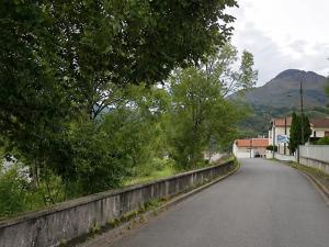 an empty road in a village with mountains in the background at Ciné Lodge Lourdes in Lourdes