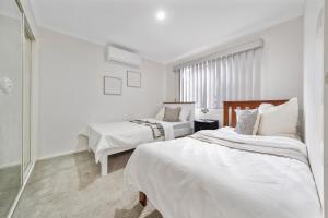 a white bedroom with two beds and a window at Relax and Rejuvenate in Vermont