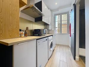 a kitchen with white cabinets and a washer and dryer at COCON HYPER CENTRE-VILLE TOUT CONFORT (8) in Ajaccio