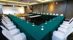 a conference room with a long green table and white chairs at Nonsi Hotel Phitsanulok in Ban Wat Tha Maprang
