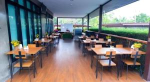 a restaurant with wooden tables and chairs and windows at Nonsi Hotel Phitsanulok in Ban Wat Tha Maprang