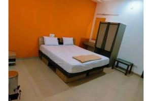 a bedroom with a bed with an orange wall at FabHotel Bhagyashri Executive in Nashik