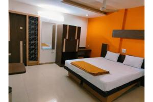 a bedroom with a bed with an orange wall at FabHotel Bhagyashri Executive in Nashik