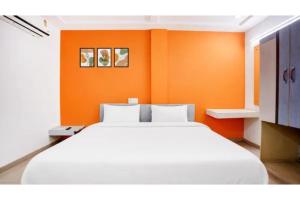 a large white bed in a room with orange walls at FabHotel Bhagyashri Executive in Nashik +7 photos