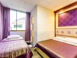 a room with two beds and a window with purple curtains at Hotel 165 in Singapore