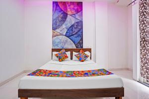 a bed in a room with a painting on the wall at FabHotel Saptshrungi in Nashik