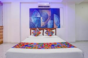 a bedroom with a bed with a painting on the wall at FabHotel Saptshrungi in Nashik