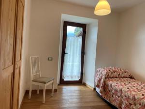 a bedroom with a bed and a chair and a window at Alpèa in Lavarone +3 photos