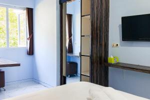 a hotel room with a bed and a television at Dprof Exclusive Guesthouse Semarang RedPartner in Jatingaleh