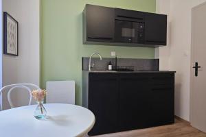 a kitchen with a white table and a microwave at Studio cocooning à 5km du centre de Strasbourg in Schiltigheim