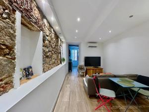 a living room with a couch and a stone wall at COCON HYPER CENTRE-VILLE TOUT CONFORT (8) in Ajaccio