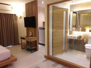 a hotel room with a bathroom with a shower and a television at W14 Pattaya in Pattaya South