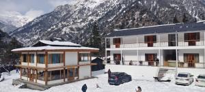 a building with cars parked in the snow in front of a mountain at Namami Harsil in Harsil