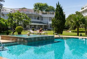 a person sitting on a bench next to a swimming pool at Azerai La Residence, Hue in Hue