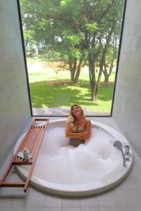 a woman sitting in a bath tub with a window at Riva Vista Riverfront Resort Chiang Rai in Chiang Rai