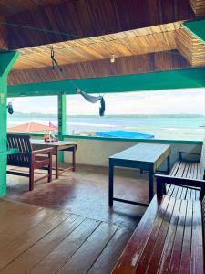 a room with benches and a table and a view of the ocean at Marlynto Surf Camp in Hilibotodane
