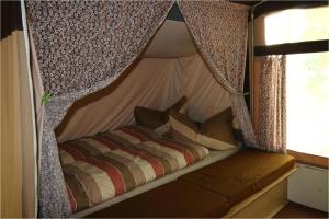 a bed in a tent with curtains and pillows at KULT TRABANT "Villa Sachsenruh" direkt am Strand in Dranske
