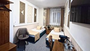 a hotel room with two beds and a chair at Cieszyński by Imperis Hotels in Cieszyn