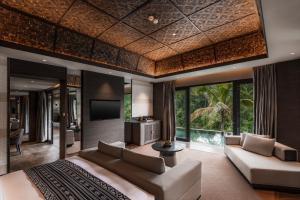 a living room with a couch and a tv at Ayatara Resort Ubud in Payangan