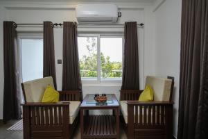 a living room with two chairs and a table and a window at Lumino Winter Castle, Munnar in Pooppara