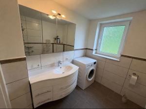 a bathroom with a sink and a washing machine at Ferienhaus am Johannesberg in Heuthen +11 photos