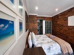 a bedroom with a bed and a brick wall at Limonite Guesthouse in Pretoria +22 photos