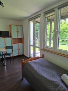 a bedroom with a bed and windows and a table at Zakątek Turysty in Gdańsk