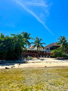 a house on a beach with palm trees in the background at Infinity Sands Resort in Siquijor