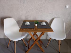 two white chairs around a wooden table with a tea set on it at Basaltic House Pedreira in Lomba da Pedreira