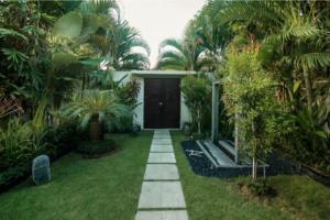 a garden with a pathway leading to a house at Arama Riverside in Legian