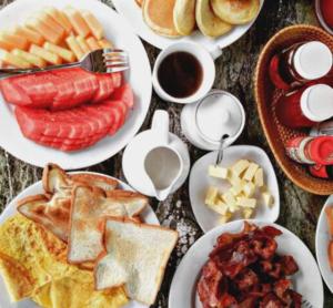 a table topped with plates of breakfast foods and coffee at Arama Riverside in Legian