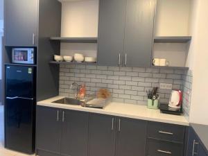 a kitchen with gray cabinets and a black refrigerator at ARVO Cam Ranh - Infinity swimming pool in Cam Ranh International Airport