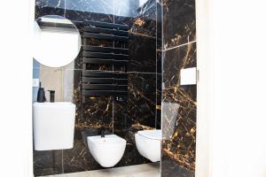 a bathroom with two toilets and a marble wall at Lidi & Miti in Bacoli