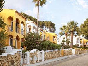 a row of yellow houses with palm trees at Aparthotel Ona Aucanada in Port d'Alcudia