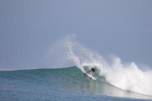 a person riding a wave on a surfboard in the ocean at Marlynto Surf Camp in Hilibotodane