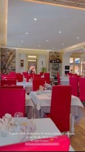 a dining room with white tables and red chairs at La Scaletta in San Colombano